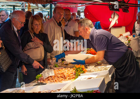 L'homme d'acheter du poisson à un décrochage en vente au marché du Rialto à Venise Italie Banque D'Images