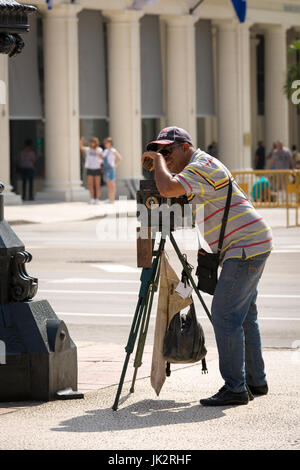 Un homme utilisant un appareil photo d'époque sur un vieux trépied en bois à la Havane, Cuba Banque D'Images