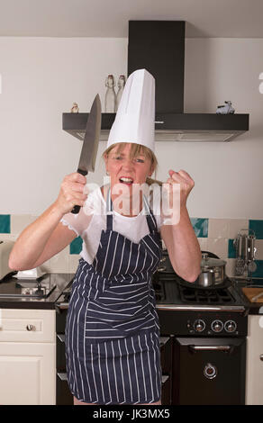 Portrait d'un très en colère chef holding un couteau de cuisine de façon menaçante Banque D'Images