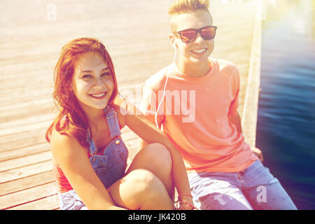 Teenage couple avec écouteurs sur quai rivière Banque D'Images