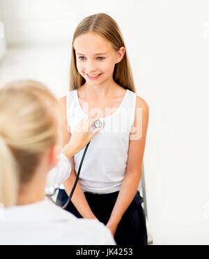 Doctor with stethoscope and girl at hospital Banque D'Images