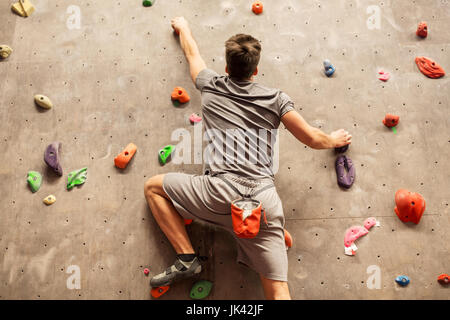 Jeune homme à l'exercice d'escalade intérieur Banque D'Images