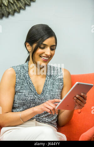 Smiling Asian woman using digital tablet Banque D'Images