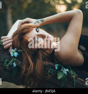 Smiling Caucasian woman laying on tree branch Banque D'Images