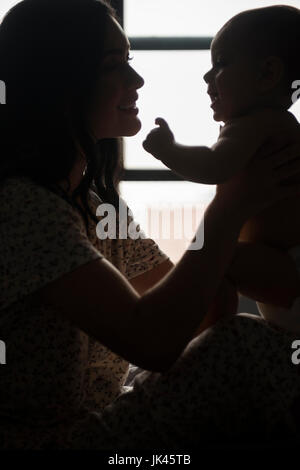 Silhouette of Caucasian mother holding baby son Banque D'Images