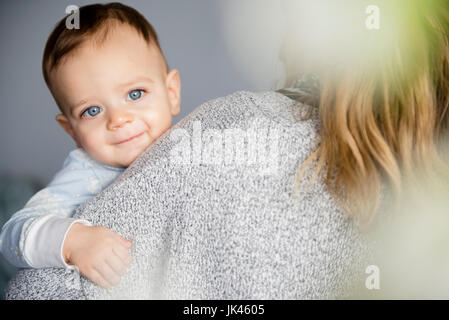 Caucasian baby boy smiling sur l'épaulement de la mère Banque D'Images