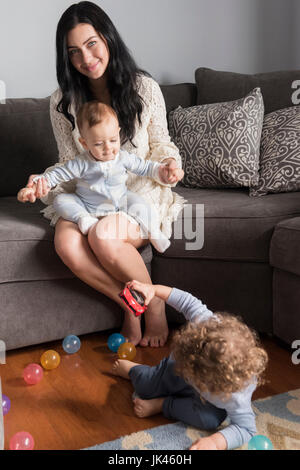 Portrait of woman sitting on sofa jouant avec fils Banque D'Images