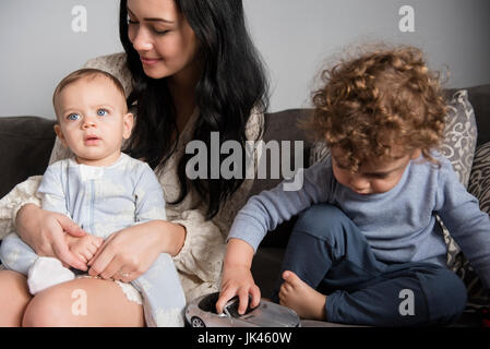 Portrait of woman sitting on sofa avec fils Banque D'Images