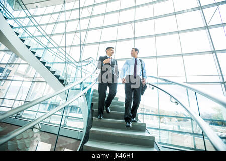 Caucasian businessmen en ordre décroissant d'escalier et de parler Banque D'Images