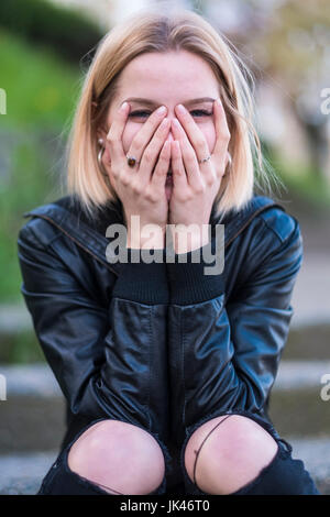 Laughing Caucasian woman covering face with hands Banque D'Images