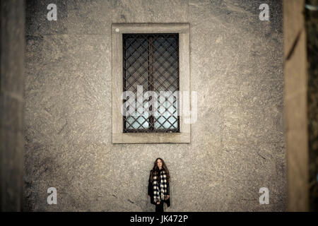 Portrait of young woman standing sous window Banque D'Images