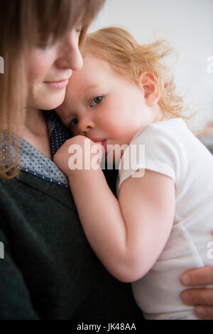 Caucasian mother holding daughter sucking thumb Banque D'Images