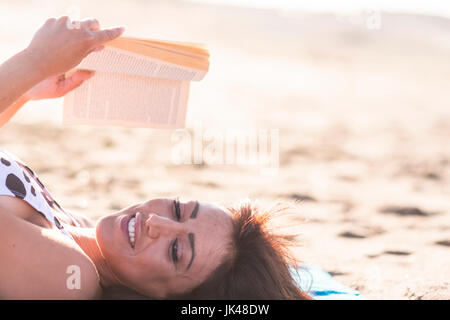 Caucasian woman laying on beach reading book Banque D'Images