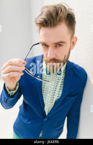 Portrait de l'homme moyen-orientale élégant avec barbe holding eyeglasses Banque D'Images
