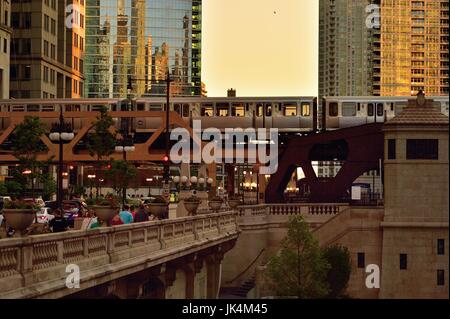 Comme le soleil crée des reflets sur une variété de surfaces, un bâtiment de Chicago LTC du train traverse la rivière.. Chicago, Illinois, USA. Banque D'Images