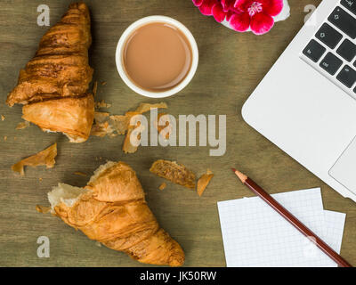 Croissant et une tasse de thé petit déjeuner ou un en-cas sur un bureau en bois haut en difficulté Banque D'Images