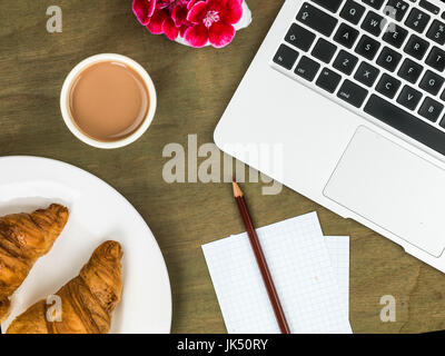 Croissant et une tasse de thé petit déjeuner ou un en-cas sur un bureau en bois haut en difficulté Banque D'Images