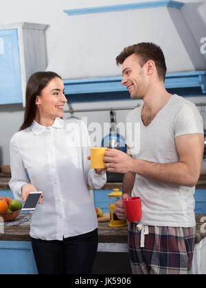 Femme en vêtements d'affaires rire avec son mari en pyjama. Banque D'Images