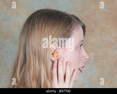 Young Girl wearing ear plug à l'intérieur de son lobe d'oreille Banque D'Images