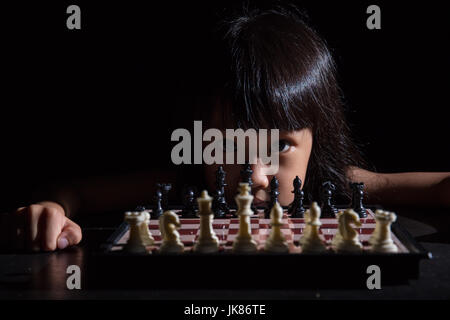 Petite fille asiatique chinois jouant aux échecs dans l'arrière-plan noir isolé Banque D'Images