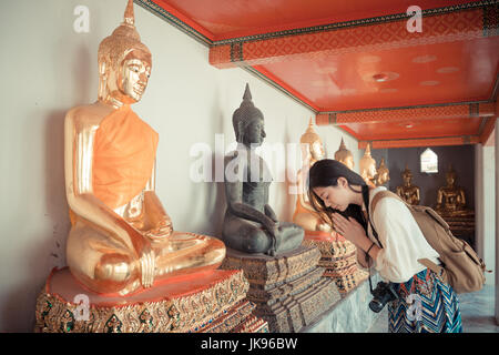 Film retro vintage style couleur photo de friendly Beautiful Girl standing in front of buddha qui souhaitent prier en bonne santé au temple de Wat Pho à Bangkok Thail Banque D'Images