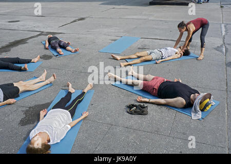 À une classe de yoga sur Astor Place à Greenwich Village, l'enseignant ajuste la position de l'élève. Banque D'Images