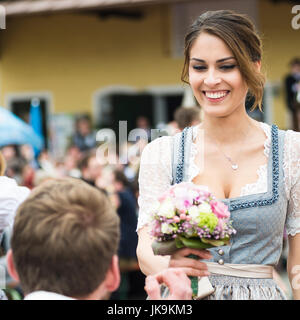 Portrait d'un jeune homme à genoux devant une femme avec un bouquet de fleurs la danse une danse folklorique bavarois traditionnel autour d'un poteau "maypole" Banque D'Images