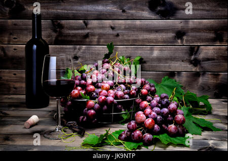 Les raisins rouges frais bouquet allongé sur feuilles sur une vieille table en bois. Banque D'Images