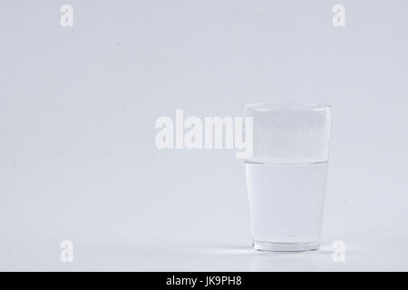 Verser de l'eau dans le verre clair sur fond blanc