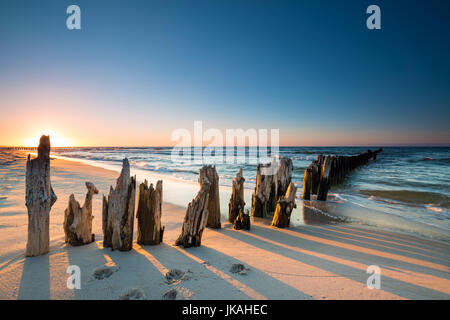 Coucher du soleil sur la plage de la mer Baltique et brise-lames en bois ancien