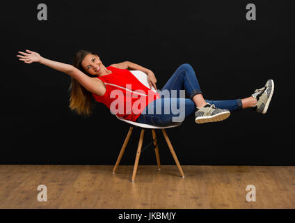 Belle jeune femme assise sur une chaise et souriant Banque D'Images