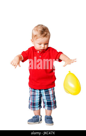 Bébé garçon debout sur le plancher avec un ballon jaune Banque D'Images