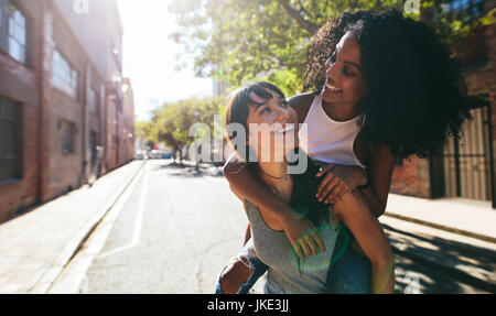 Tourné en plein air de jeune femme portant son amie sur son dos. Deux jeunes femme s'amusant on city street. Banque D'Images