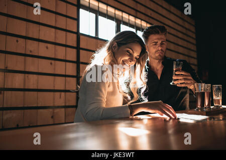 Jeune couple au bar dégustation de différentes variétés de bières artisanales. Belle jeune femme avec son petit ami au bar ayant des bières. Banque D'Images