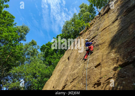 Male rock climber climbing à Yarncliffe Quarry, Derbyshire Banque D'Images