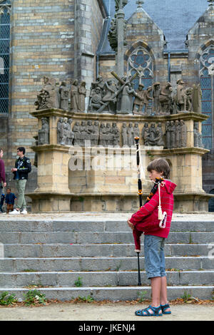 Un jeune musicien traditionnel breton devant le calvaire de Plougastel-Daoulas, Finistère, Bretagne, France .Jeune joueur de biniou Banque D'Images