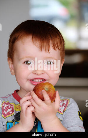 Un jeune, homme, enfant bénéficiant d'un frais, sain, apple. prises dans la maison en utilisant la lumière naturelle Banque D'Images