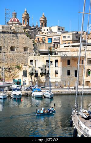 Les passagers à bord d'un bateau-taxi Dghajsa traditionnelle maltaise dans le port avec des vues vers Senglea Vittoriosa, au bord de l'eau, Malte, l'Europe. Banque D'Images