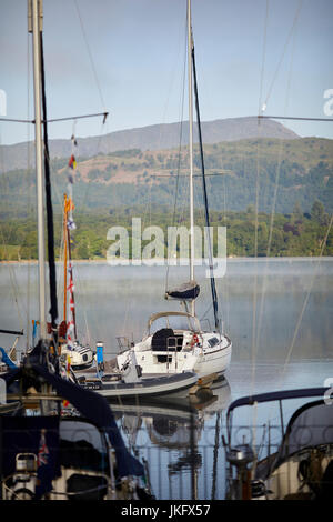 Matin brume sur un grand lac Windermere Cumbria en's Lake District National Park, atteint à peu de bateaux de plaisance en bois, près de Ambleside Banque D'Images