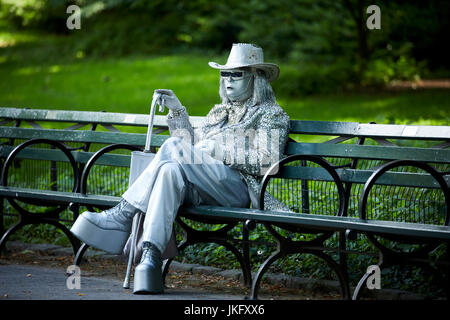 La ville de New York, Manhattan, Central Park silver diamante costume couvert sur des bancs d'attente busker posant pour des conseils Banque D'Images