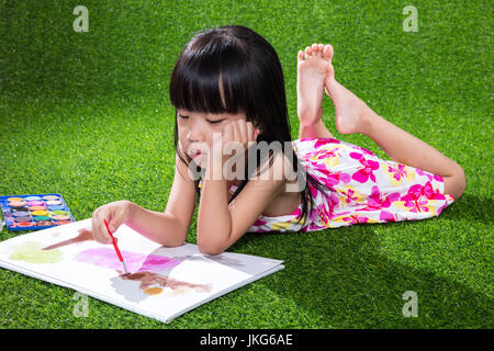 Chinois asiatique petite fille couchée sur l'herbe le dessin et la peinture Banque D'Images