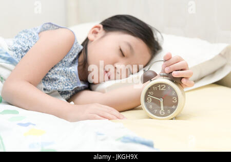 Part girl reaching out for réveil le matin, l'heure du coucher Banque D'Images