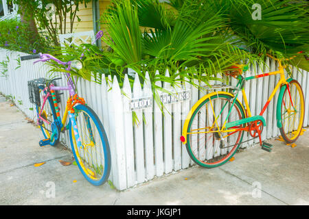 Deux bicyclettes peint de couleurs vives, se penchant sur les piquets de clôture sur le coin de la rue résidentielle Banque D'Images