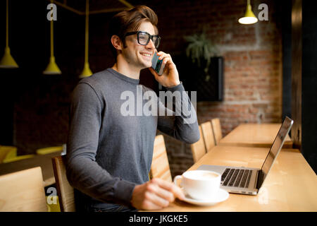 Beau jeune freelancer dans les verres d'oeil parler smartphone à coffre Banque D'Images
