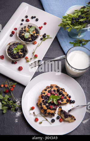 Muffin aux myrtilles et petits fruits fraises sur une assiette blanche et une table en bois servi avec du lait et de baies fraîches et Banque D'Images