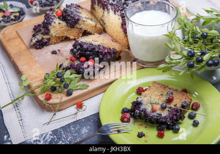 Berry cake et muffins aux bleuets et fraises sur une plaque verte et un bureau en bois servi avec du lait et de baies fraîches et Banque D'Images
