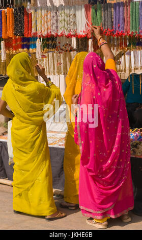 Mesdames indien en sari coloré de shopping pour les bijoux at a market stall à Pushkar, Rajasthan, India Banque D'Images