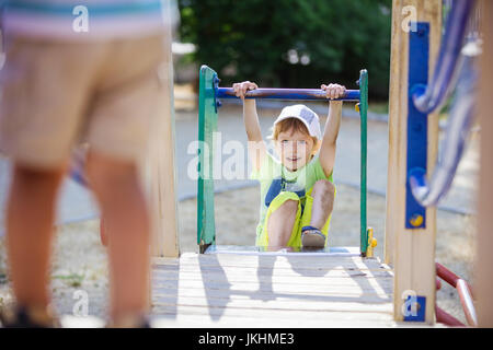 Cute Young boy climbing up glisser sur aire Banque D'Images