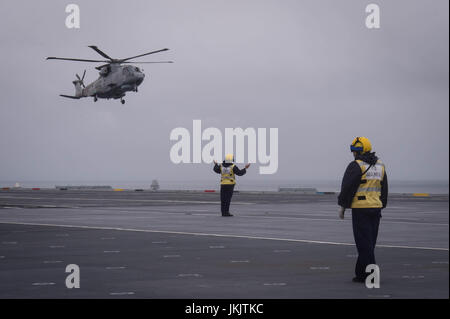 Guide de l'équipage d'un hélicoptère sur le pont du HMS Queen Elizabeth, comme la Royal Navy nouveau porte-avions appareille de Southampton pour la dernière d'une série d'essais en mer. Banque D'Images