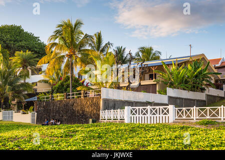 Blue Bay, Ile Maurice - Décembre 27, 2015 : Les gens sont assis sur l'herbe près du mur de la chambre et de palmiers tropicaux sur la plage de Blue Bay à sunse Banque D'Images